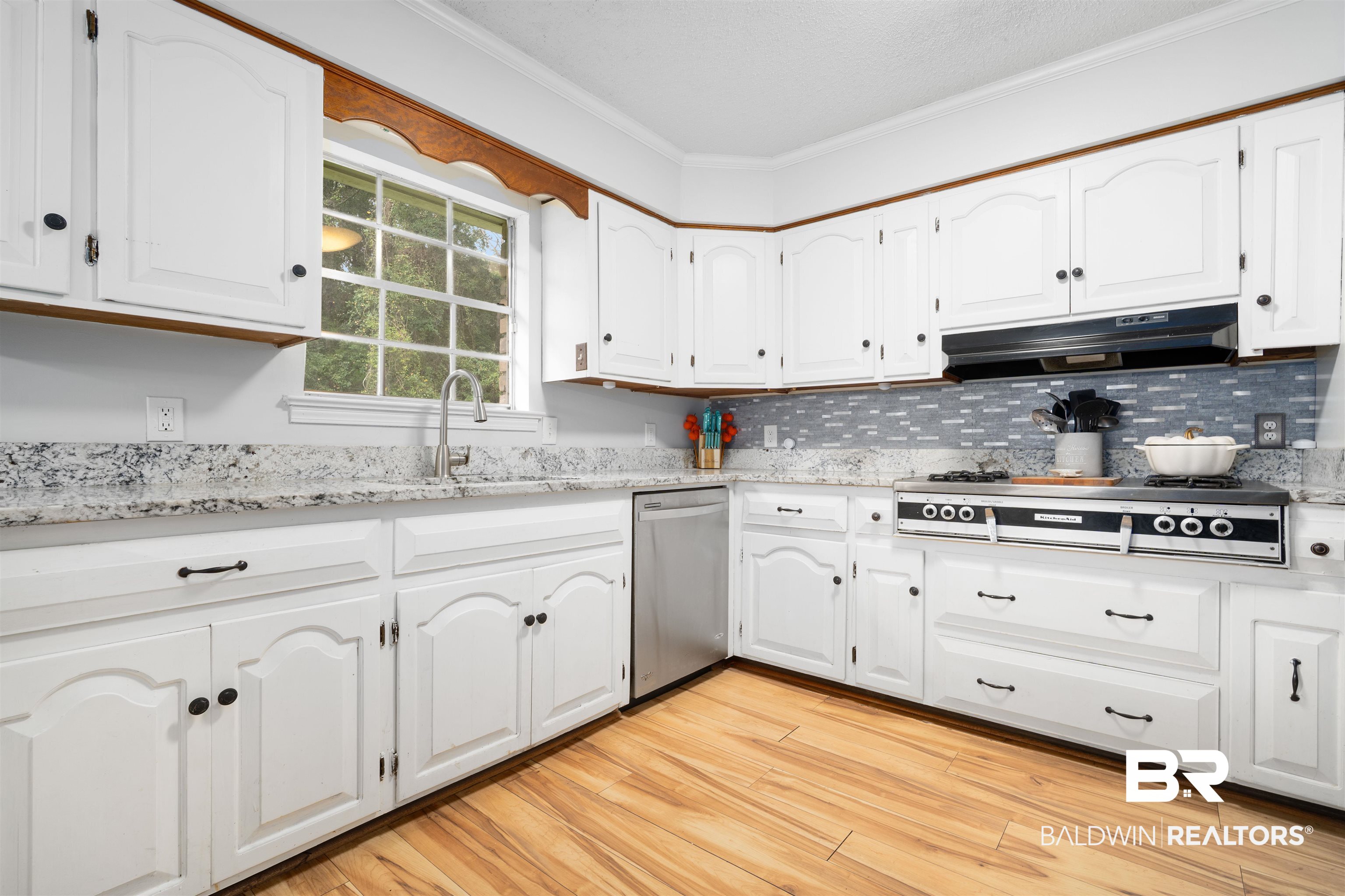 7807 Yorkhaven Road Mobile, AL 36695 - Photo 7 of 34 Kitchen with white cabinets, light stone counters, crown molding, stainless steel appliances, and light wood-style flooring