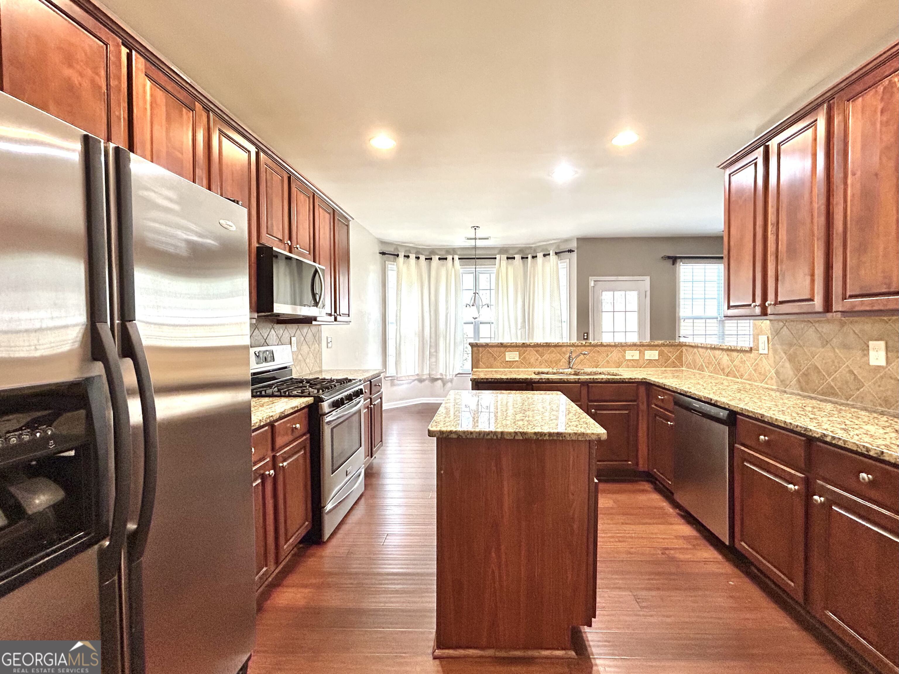 7613 Cedar Grove Court Fairburn, GA 30213 - Photo 28 of 61 a large kitchen with stainless steel appliances kitchen island granite countertop a sink and cabinets