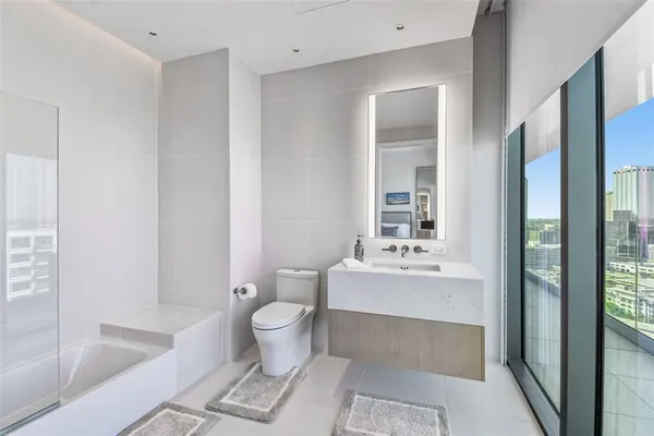 a bathroom with a bathtub shower sink mirror and toilet
