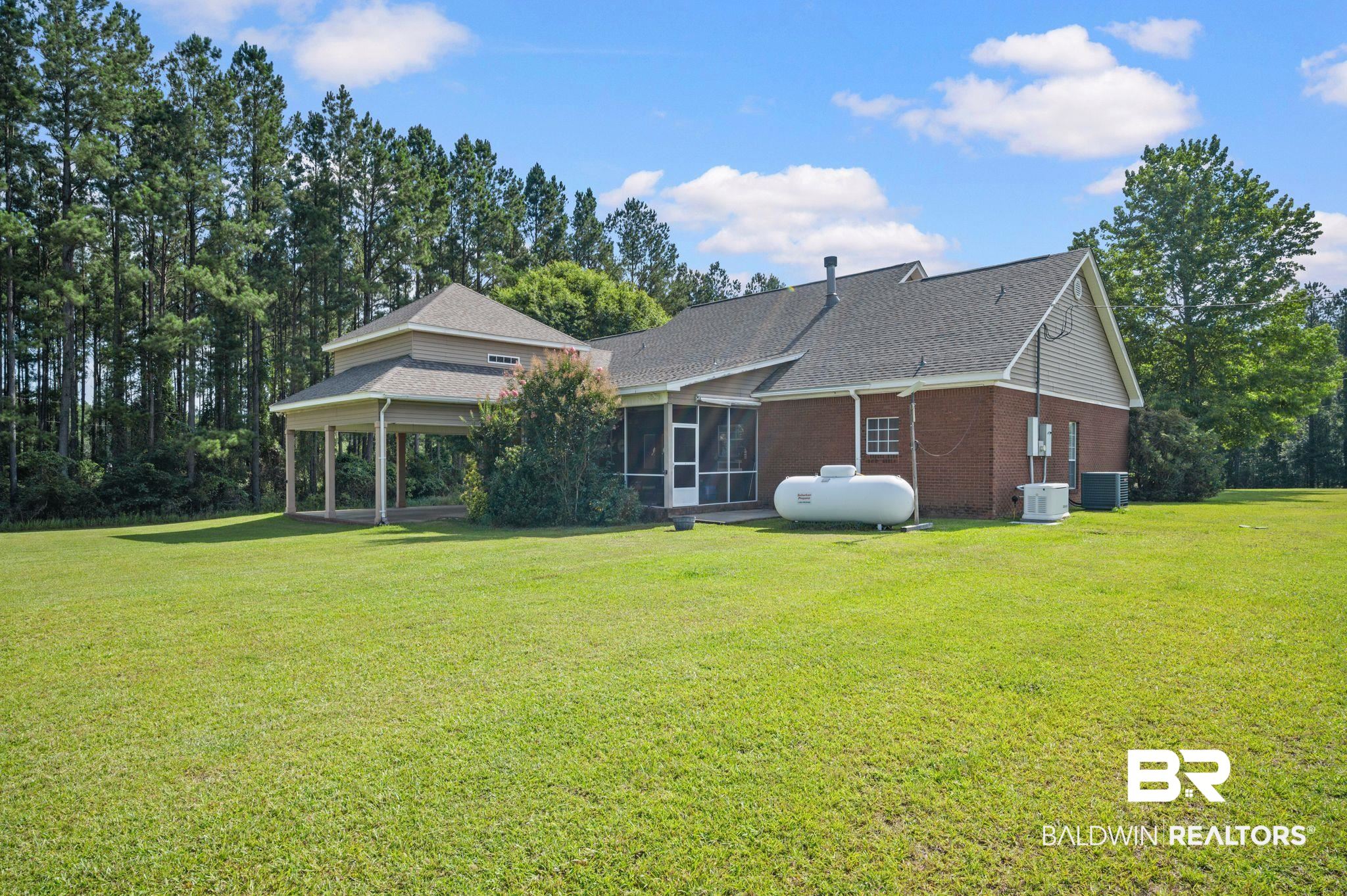 48513 Phillipsville Road Bay Minette, AL 36507 - Photo 42 of 50 Rear view of house featuring a sunroom, a yard, roof with shingles, and brick siding