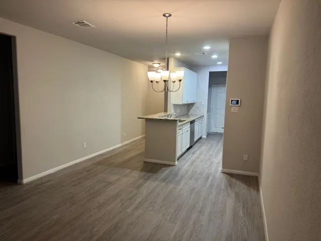 a view of a room with wooden floor and kitchen view