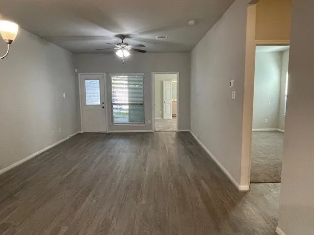 a view of an empty room with wooden floor and a window