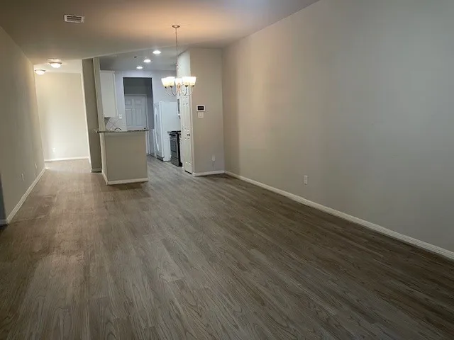 a view of an empty room with wooden floor and chandelier