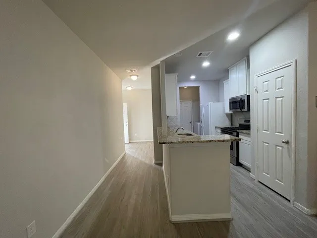 a view of kitchen with microwave a stove and wooden floor