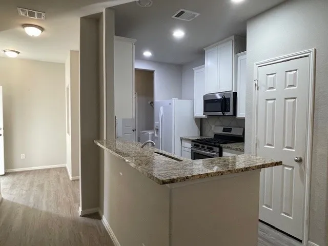a kitchen with granite countertop a sink a counter top space stainless steel appliances and cabinets