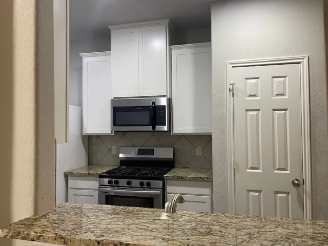 a kitchen with stainless steel appliances granite countertop a stove a microwave and a refrigerator