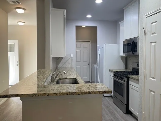 a kitchen with granite countertop a sink a stove and refrigerator