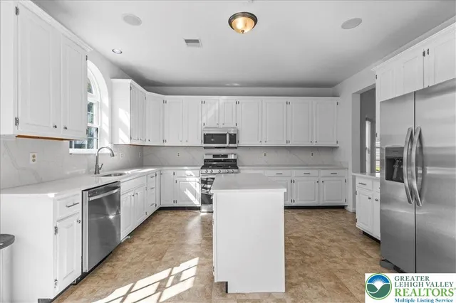 a kitchen with a sink a refrigerator and white cabinets