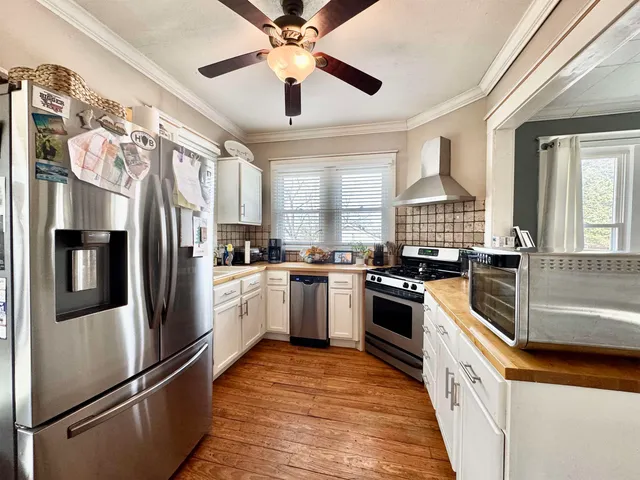 a kitchen with stainless steel appliances kitchen island granite countertop a refrigerator a sink dishwasher a stove and a refrigerator