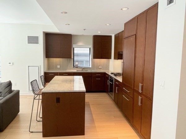 580 Washington Street, Unit 3C Boston, MA 02111 - Photo 4 of 12 a kitchen with kitchen island granite countertop a sink and a refrigerator