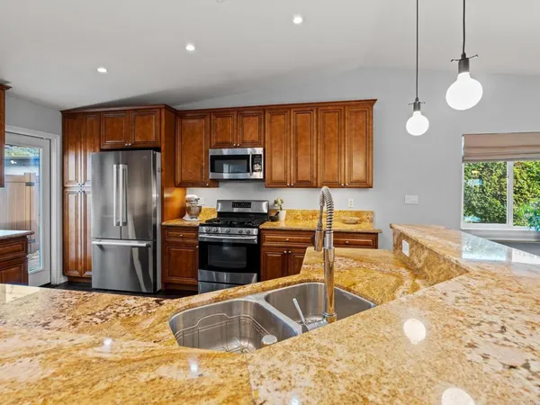 a kitchen with stainless steel appliances granite countertop a sink a stove and a refrigerator