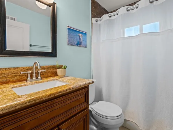a bathroom with a granite countertop sink toilet and a mirror