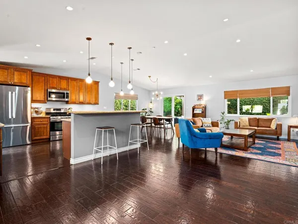 a kitchen with stainless steel appliances granite countertop a stove top oven a dining table and chairs with wooden floor
