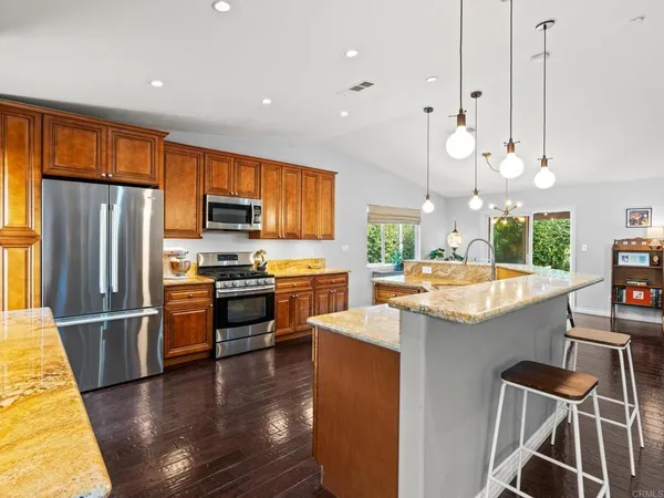 a kitchen with stainless steel appliances granite countertop a refrigerator a stove top oven a sink dishwasher and white cabinets with wooden floor
