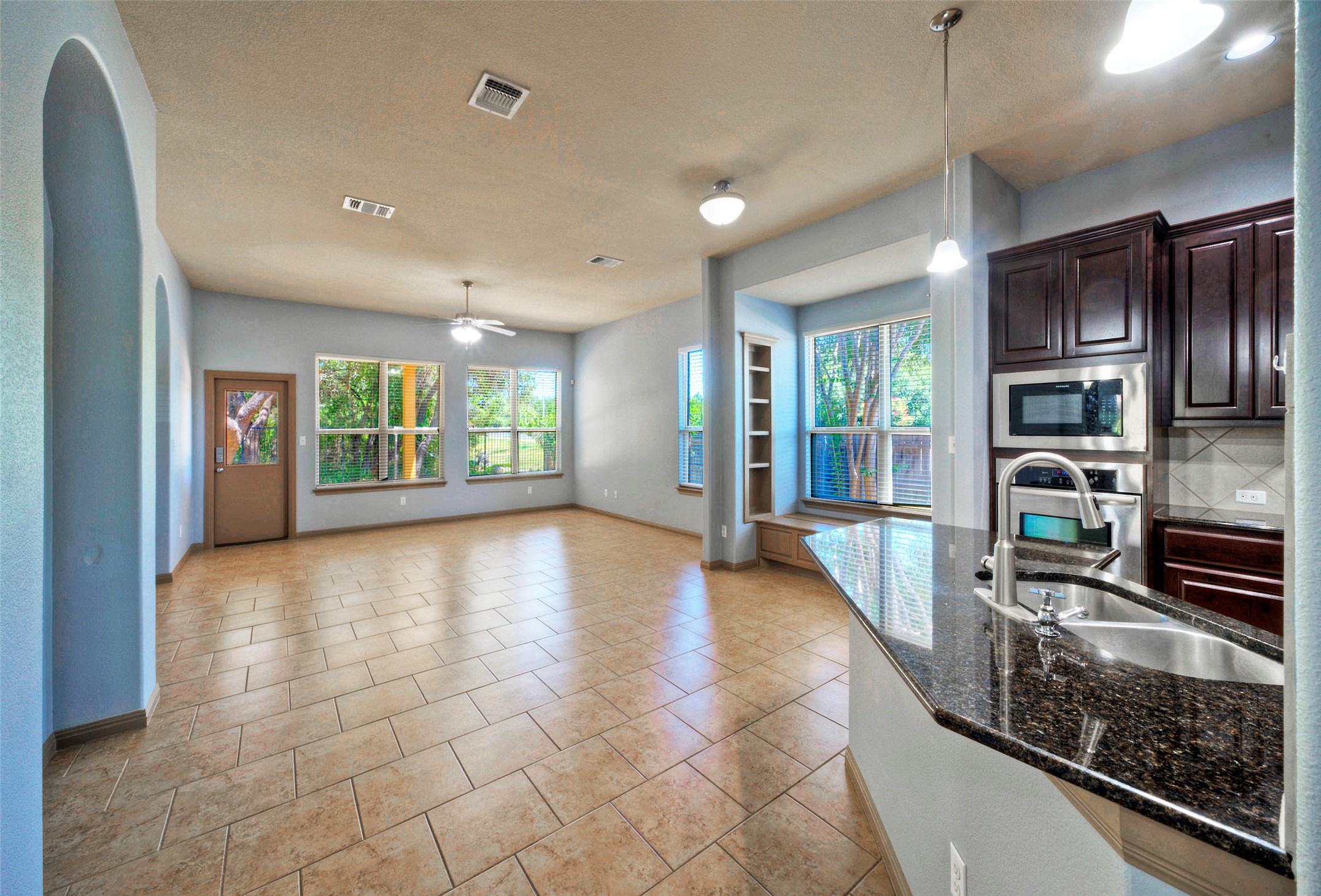 1601 Nelson Ranch Loop Cedar Park, TX 78613 - Photo 11 of 30 Tiled flooring flows through a grand living space overlooked by a modern granite kitchen.