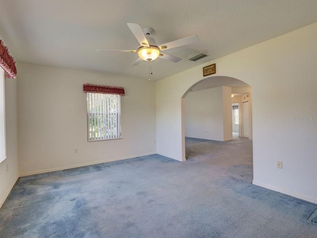 11340 Southwest 76th Circle Ocala, FL 34476 - Photo 13 of 42 an empty room with a chandelier fan and windows
