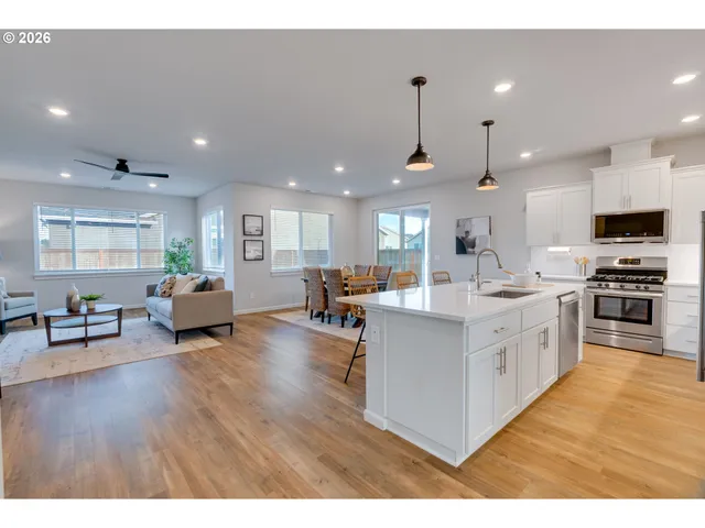 a large white kitchen with lots of counter space a sink appliances and living room