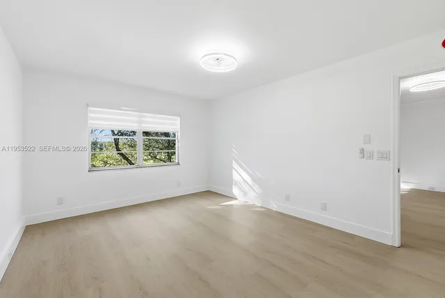 an empty room with wooden floor and window