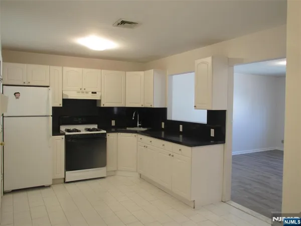 a kitchen with granite countertop white cabinets and stainless steel appliances