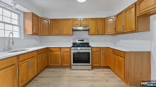 a kitchen with stainless steel appliances granite countertop a stove a sink and a microwave