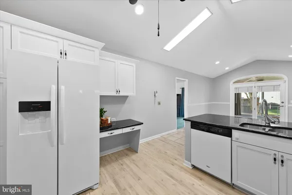 a kitchen with granite countertop a refrigerator a sink and white cabinets
