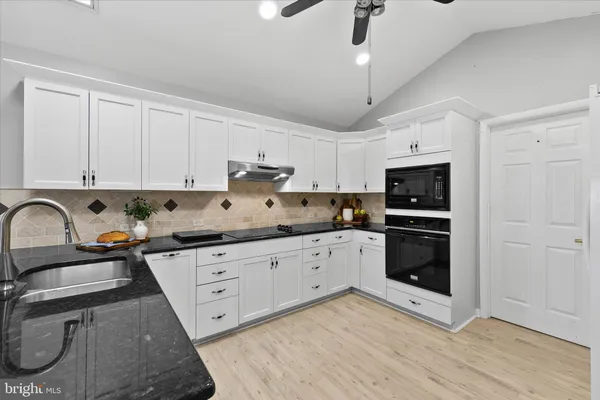 a kitchen with granite countertop a stove a sink and a refrigerator