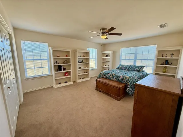 a spacious bedroom with a bed a dresser and shelf