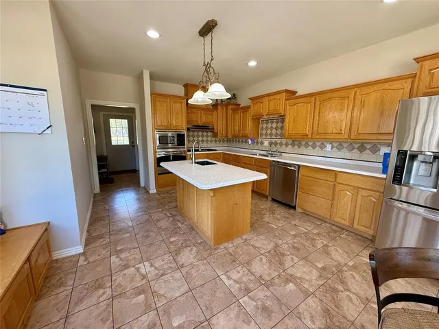 a large kitchen with kitchen island a stove a sink dishwasher and white cabinets with wooden floor