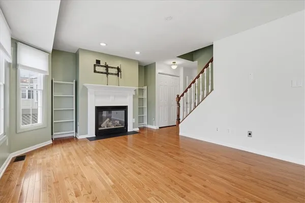 a view of an empty room with wooden floor fireplace and a window