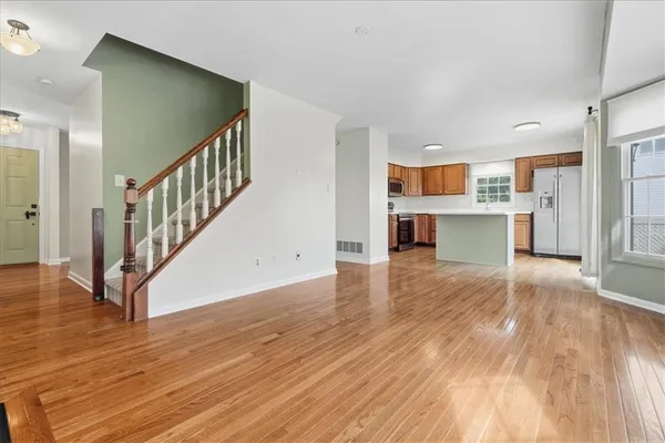 a view of a kitchen and an empty room with wooden floor