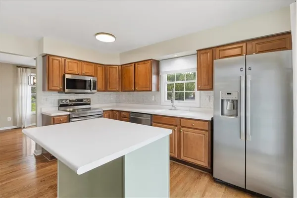 a kitchen with stainless steel appliances a stove a sink a refrigerator a center island and a window
