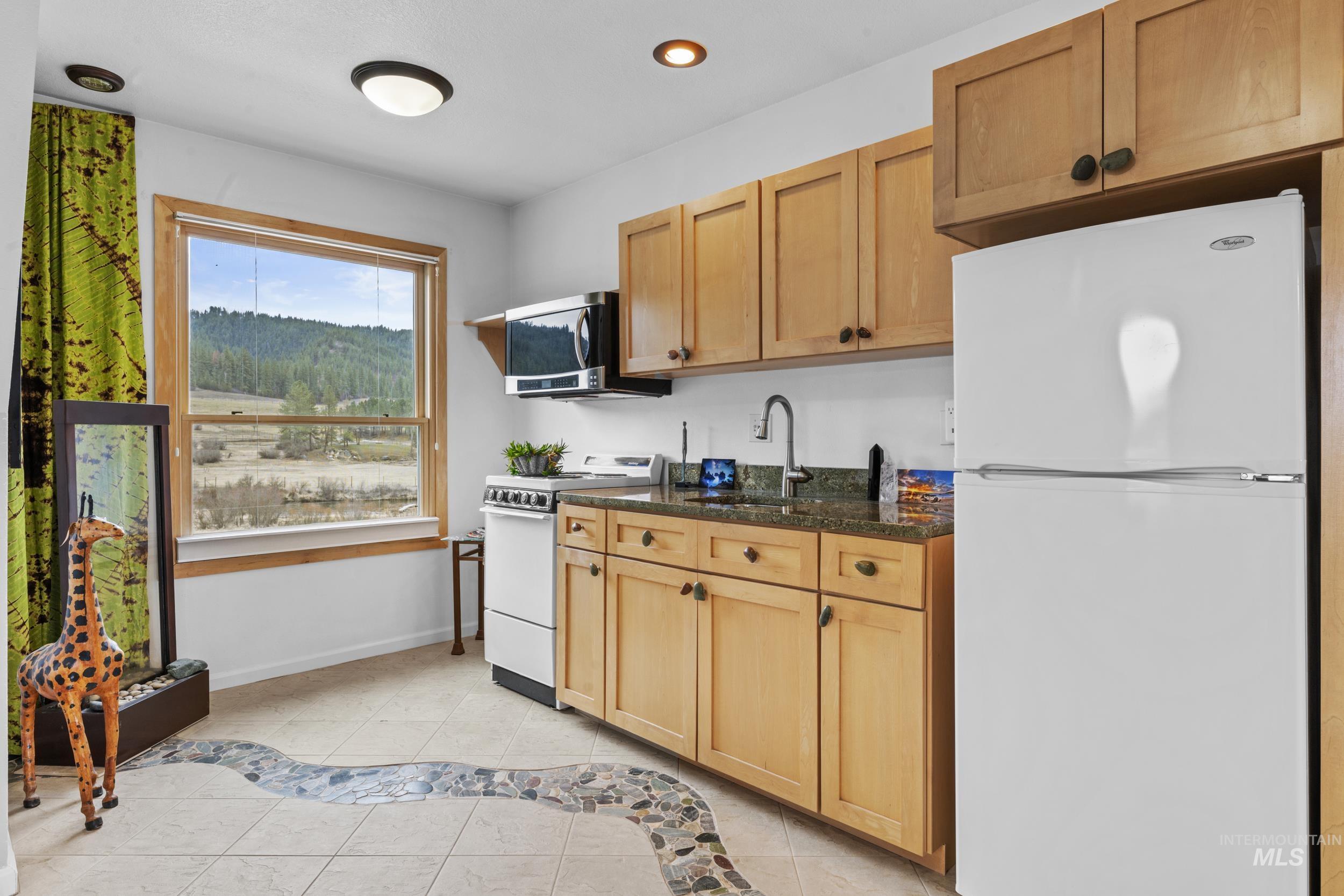 69 River Ranch Road Garden Valley, ID 83622 - Photo 25 of 50 Kitchen featuring white appliances, light tile patterned floors, dark stone countertops, and recessed lighting