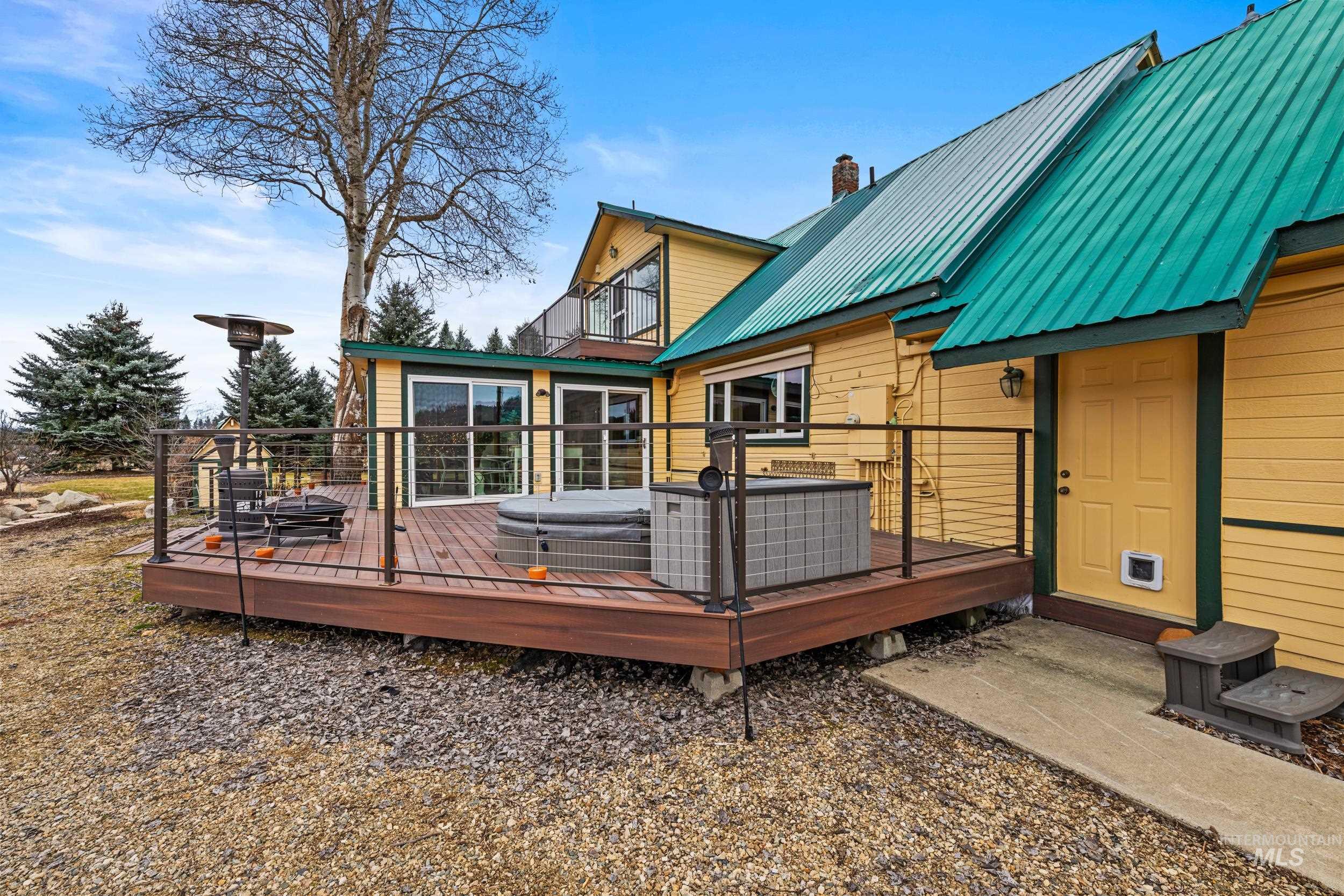 69 River Ranch Road Garden Valley, ID 83622 - Photo 40 of 50 Back of house featuring a metal roof, a wooden deck, a chimney, and a jacuzzi