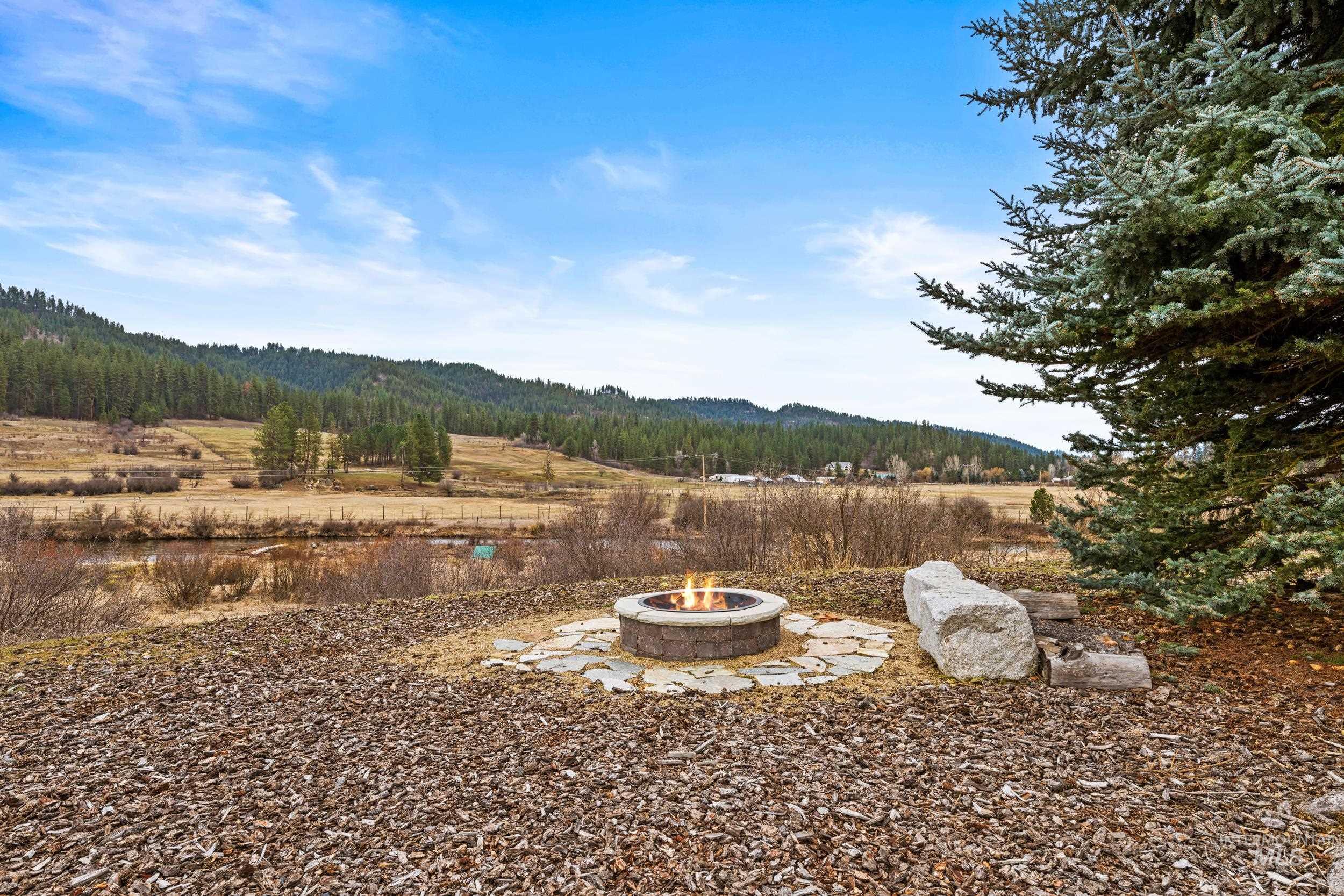 69 River Ranch Road Garden Valley, ID 83622 - Photo 45 of 50 View of yard featuring an outdoor fire pit, a patio, a wooded view, and a mountain view