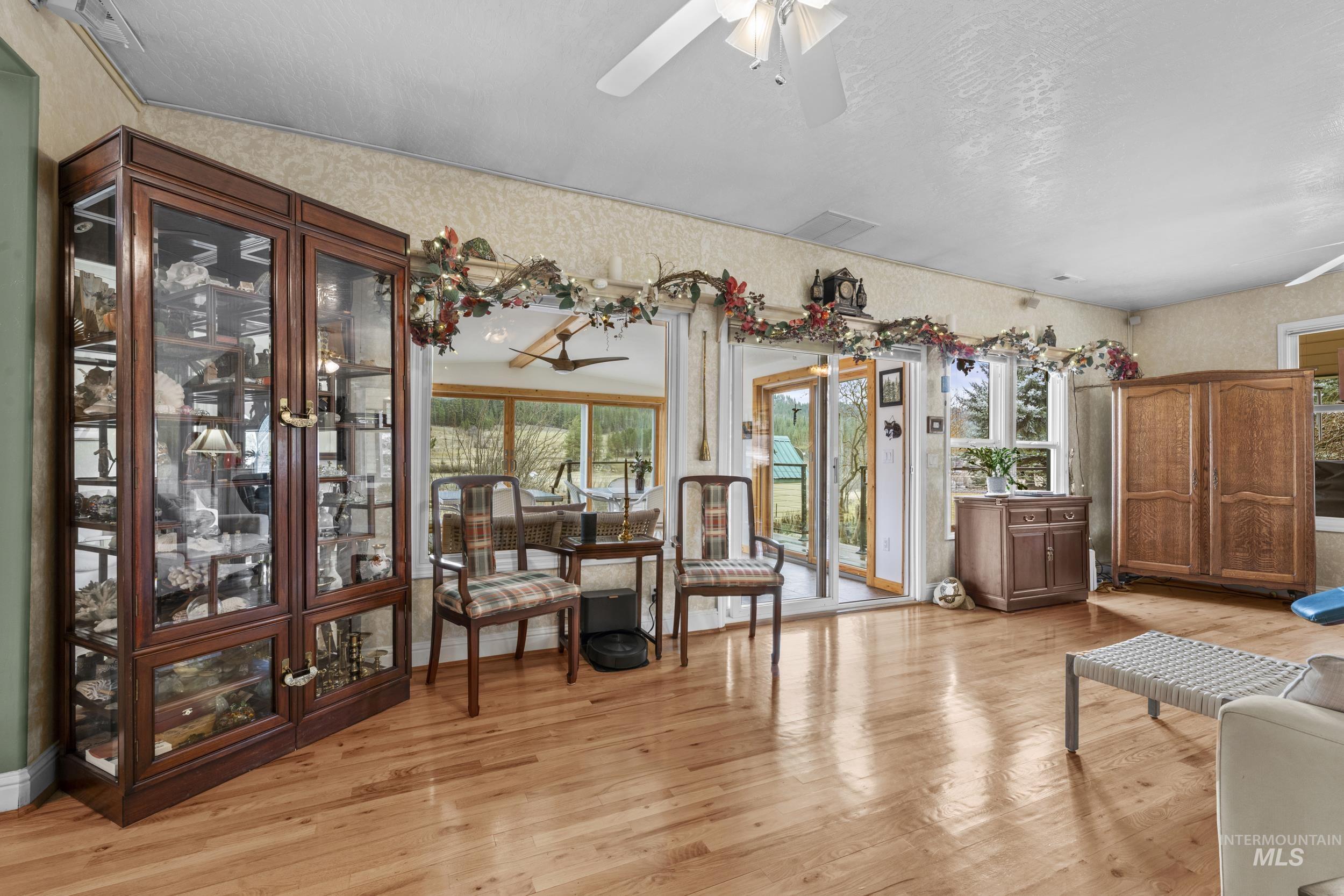 69 River Ranch Road Garden Valley, ID 83622 - Photo 8 of 50 Living area featuring light wood-type flooring, wallpapered walls, ceiling fan, and a textured ceiling