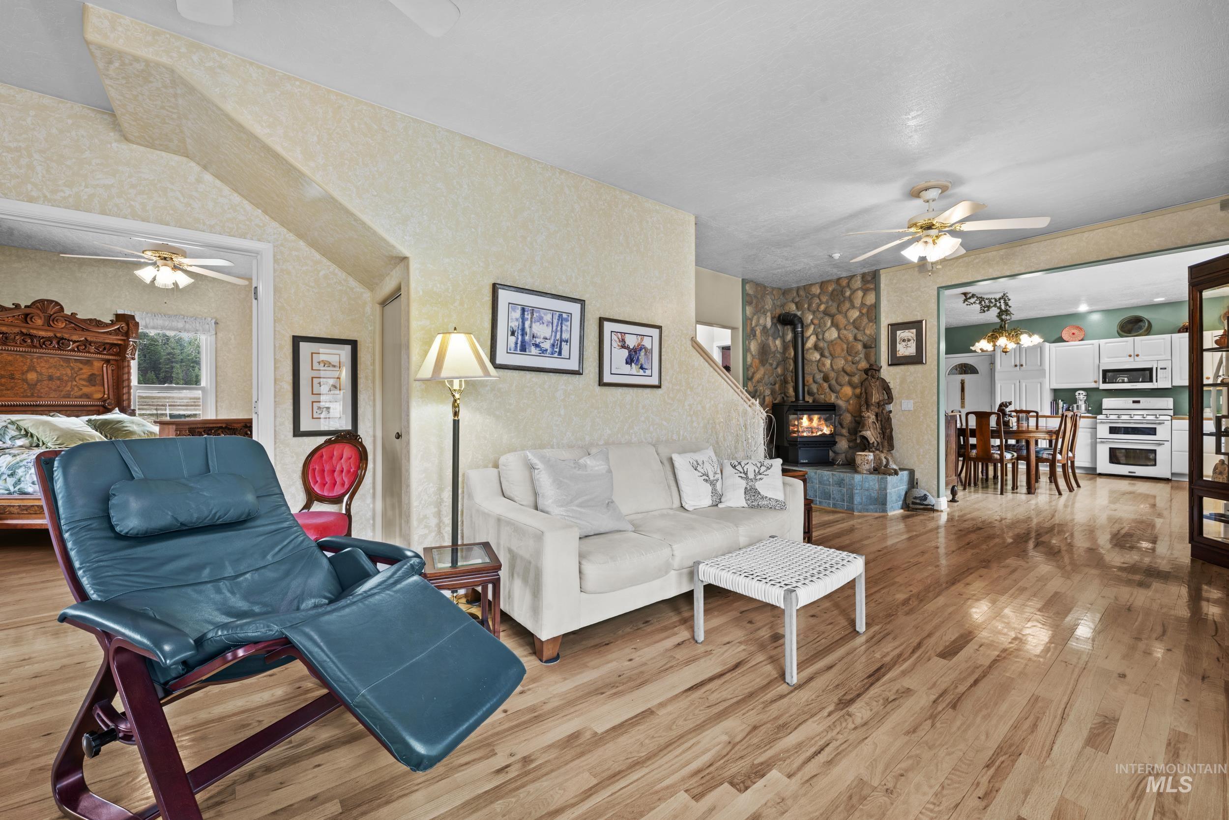 69 River Ranch Road Garden Valley, ID 83622 - Photo 10 of 50 Living area with ceiling fan, light wood-type flooring, a wood stove, and hanging lights