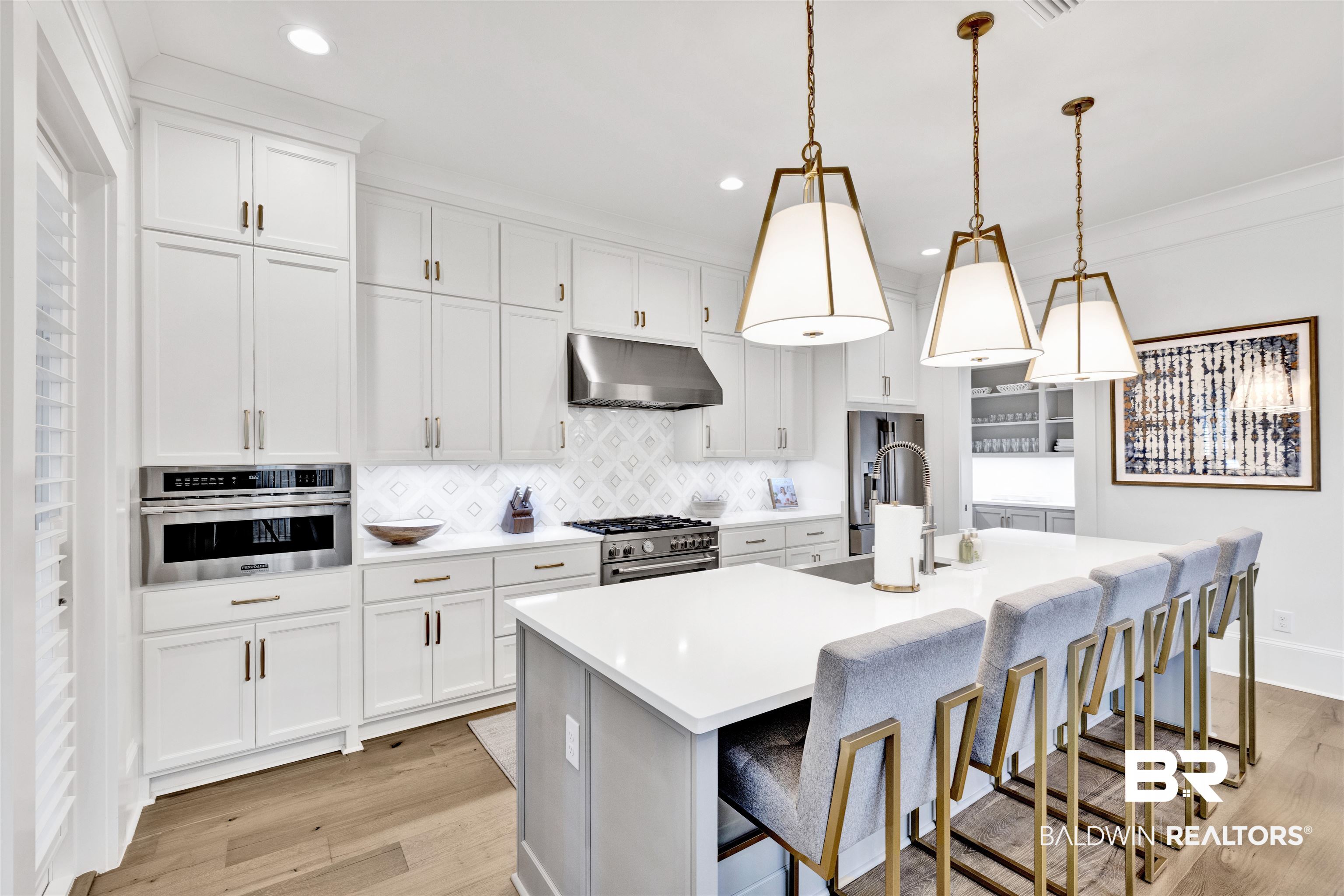 861 Inlet Circle Gulf Shores, AL 36542 - Photo 6 of 54 Kitchen featuring a breakfast bar area, white cabinets, a kitchen island with sink, light wood-style flooring, and ornamental molding
