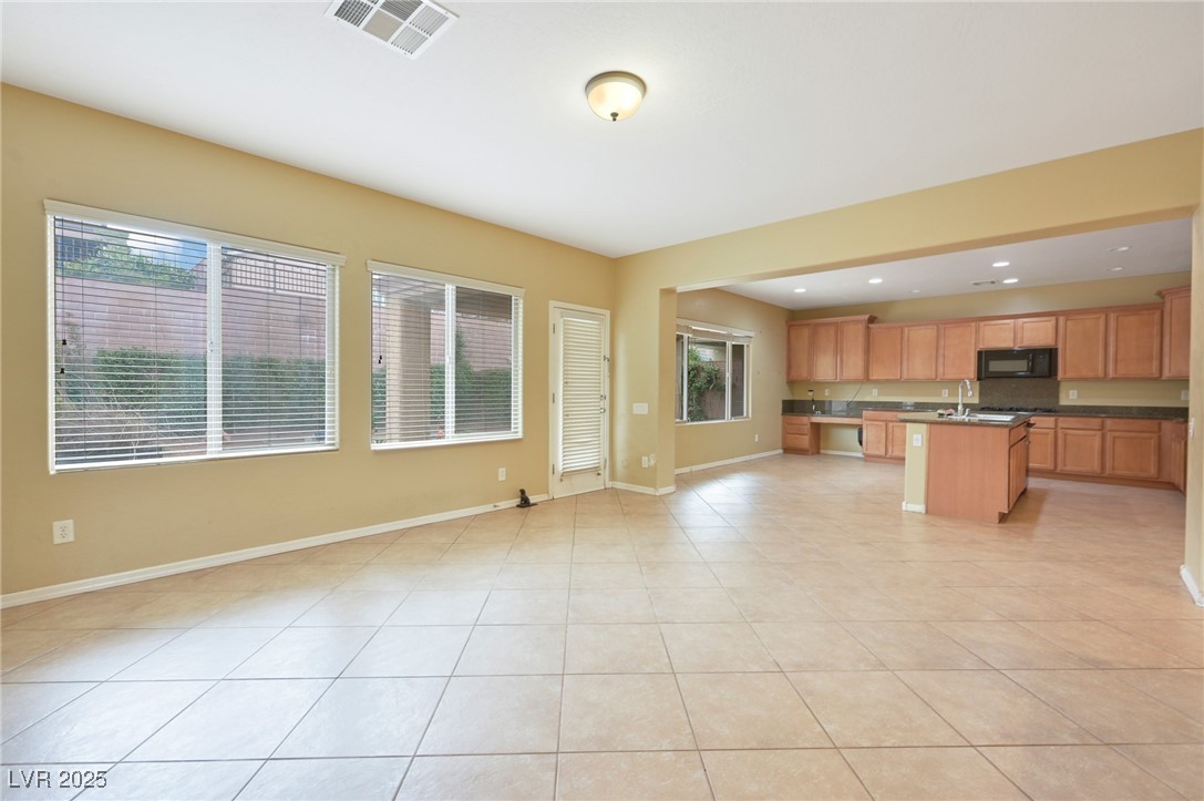 2289 Manosque Lane Henderson, NV 89044 - Photo 35 of 35 Kitchen featuring dark countertops, open floor plan, a kitchen island with sink, black microwave, and light tile patterned floors