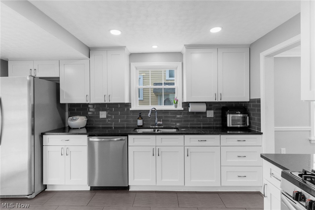 3625 Ludgate Road Cleveland, OH 44120 - Photo 4 of 16 Kitchen featuring backsplash, tile floors, white cabinets, sink, and appliances with stainless steel finishes