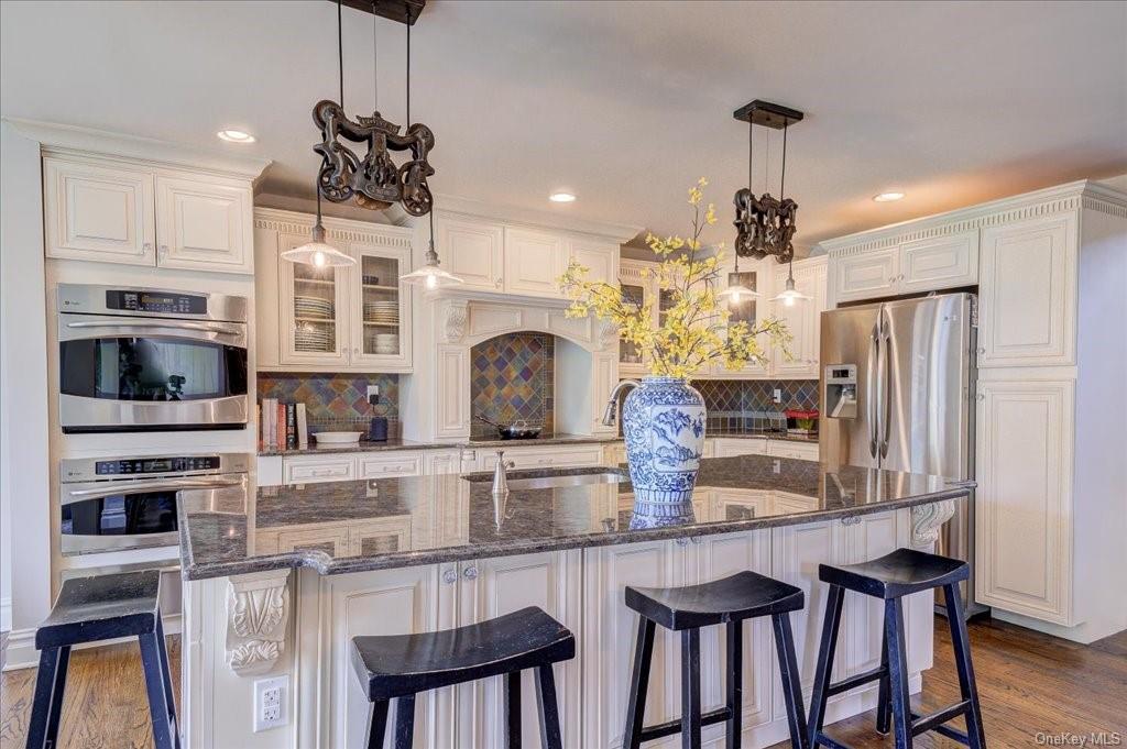 a kitchen with stainless steel appliances granite countertop a kitchen island and a refrigerator in it