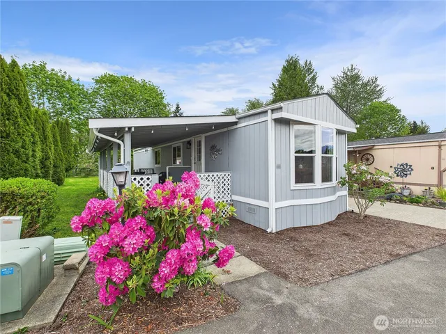 a view of a white house with a flower garden and chair