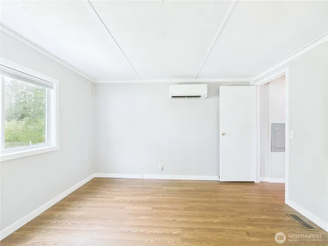 a view of an empty room with wooden floor and a window