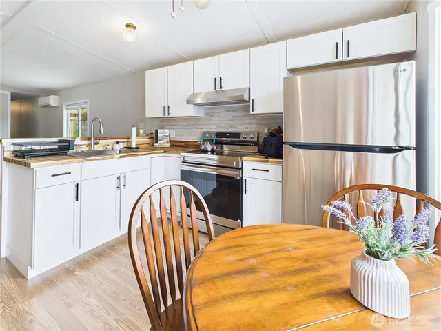 a kitchen with stainless steel appliances granite countertop a refrigerator a sink a stove a dining table and chairs