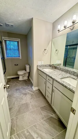 a bathroom with a granite countertop sink toilet and shower
