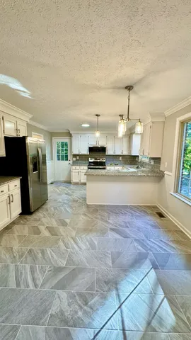 a view of a kitchen with refrigerator and white cabinets