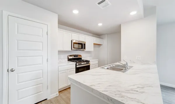 a kitchen with a refrigerator stove and white cabinets