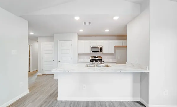 a large white kitchen with kitchen island a sink stainless steel appliances and cabinets