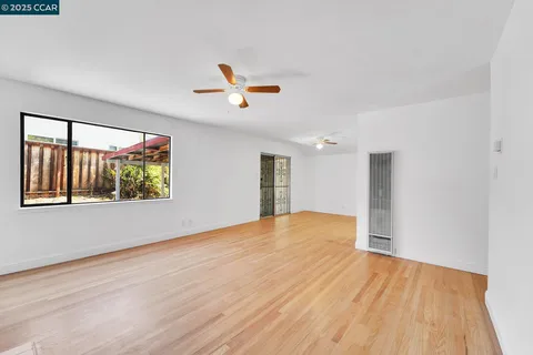 a view of empty room with wooden floor and fan