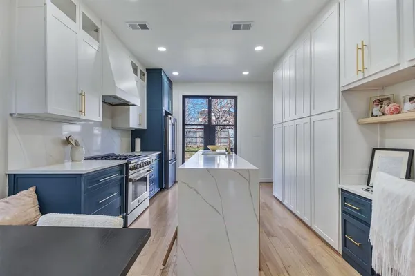 a large kitchen with stainless steel appliances granite countertop a refrigerator a sink dishwasher a stove and a dining table with wooden floor