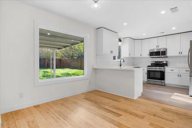 a kitchen with stainless steel appliances granite countertop a stove a sink and a white refrigerator with wooden floor